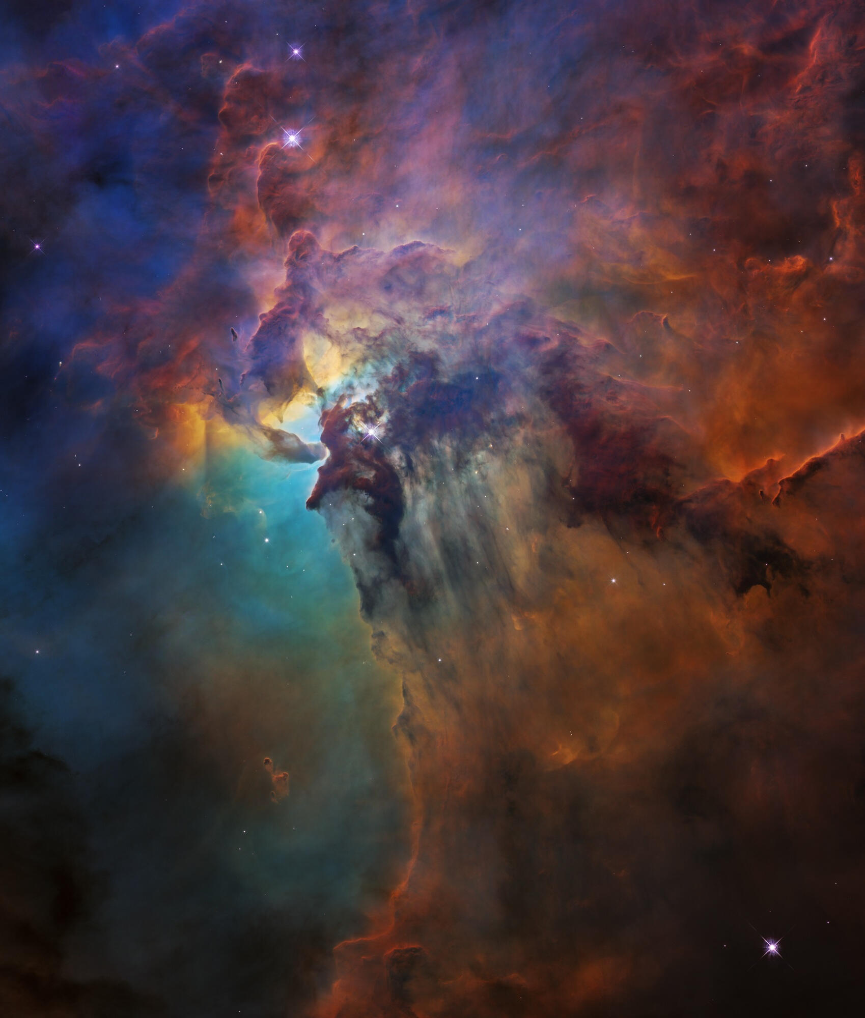 A vibrant visible-light image from the Hubble Space Telescope showing the heart of the Lagoon Nebula. A fantasy landscape of ridges, cavities, and mountains of glowing gas and dust is sculpted by intense radiation from the monster young star, Herschel 36,